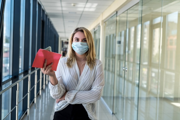 Affascinante giovane signora in una mascherina medica che tiene una busta con i soldi nel centro commerciale. concetto di finanza