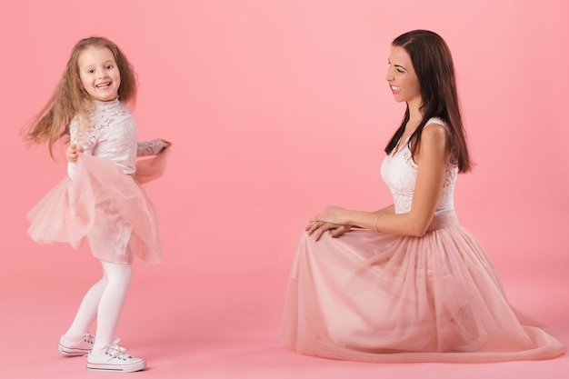 Affascinante madre e figlia sorridente su sfondo rosa