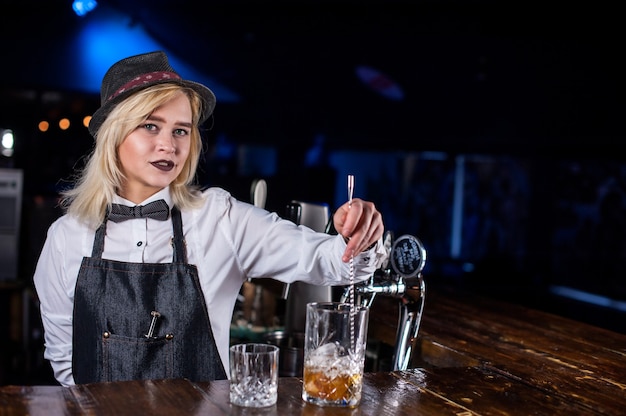 Affascinante ragazza barista sta versando un drink nel night club