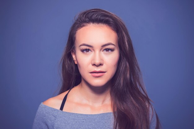 Affascinante ragazza con lunghi capelli scuri su sfondo blu