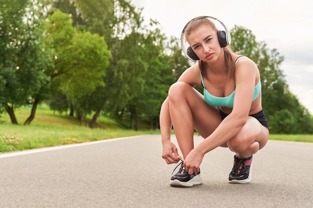 Affascinante ragazza fa un allenamento nel parco Il concetto di uno stile di vita sano Attrezzature sportive Pubblicità in stile fitness