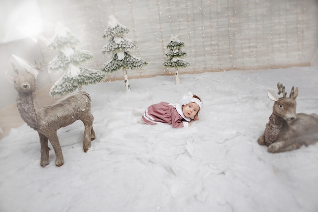 Affascinante ragazza sdraiata sulla slitta della neve di Natale intorno al cervo, girato in studio.