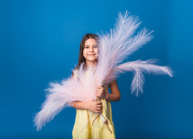 Affascinante ragazza su sfondo blu studio bella bruna con piume Concetto di generazione Z