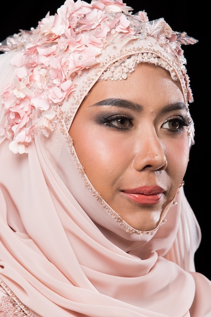 Affascinante sposa araba musulmana asiatica in abito da sposa rosa antico dolce ricamo di perline di pizzo e foulard hijab, primo piano su Fashion Make up Eyes Face, studio di illuminazione sfondo nero isolato.
