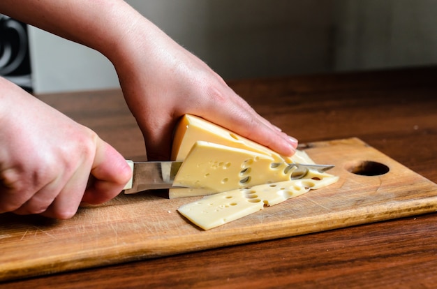 Affettare il formaggio su una tavola di legno.