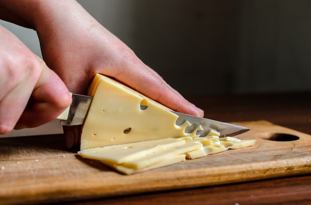 Affettare il formaggio su una tavola di legno.