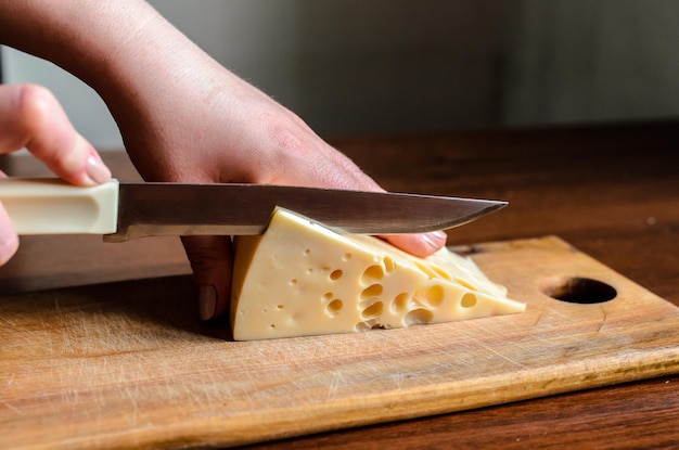 Affettare il formaggio su una tavola di legno