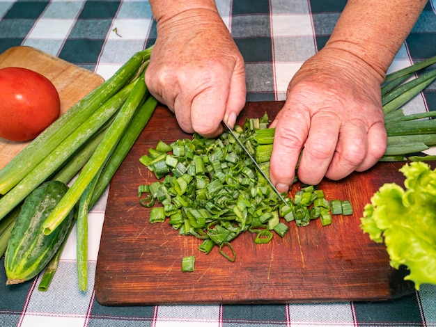 Affettare le cipolle verdi con un coltello su un tagliere