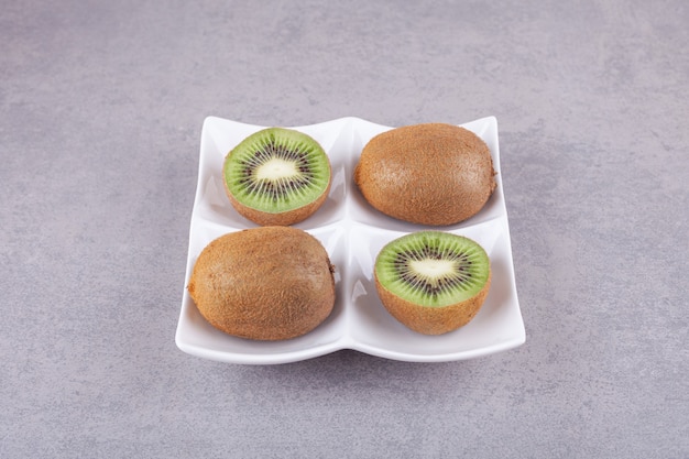 Affettato delizioso kiwi con foglie poste su un piatto verde.