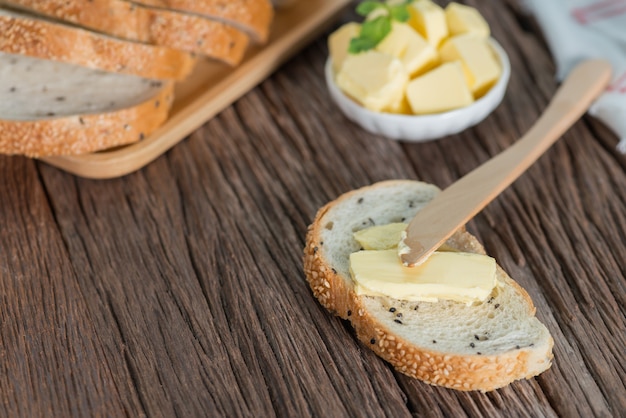 Affettato di pane al sesamo con burro su tavola di legno.