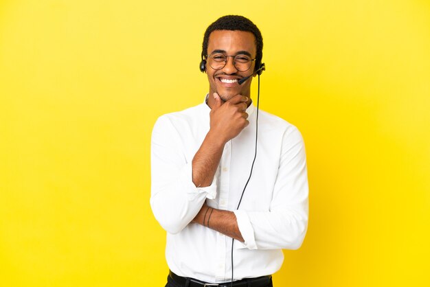 African American Telemarketer uomo che lavora con un auricolare su una superficie gialla isolata con occhiali e sorridente and