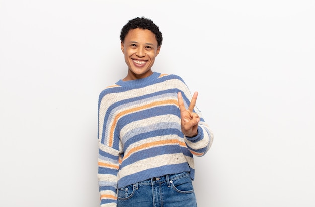 Afro giovane donna nera sorridente e guardando amichevole, mostrando il numero due o il secondo con la mano in avanti, il conto alla rovescia