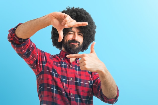 Afro uomo concentrando con le dita sullo sfondo colorato