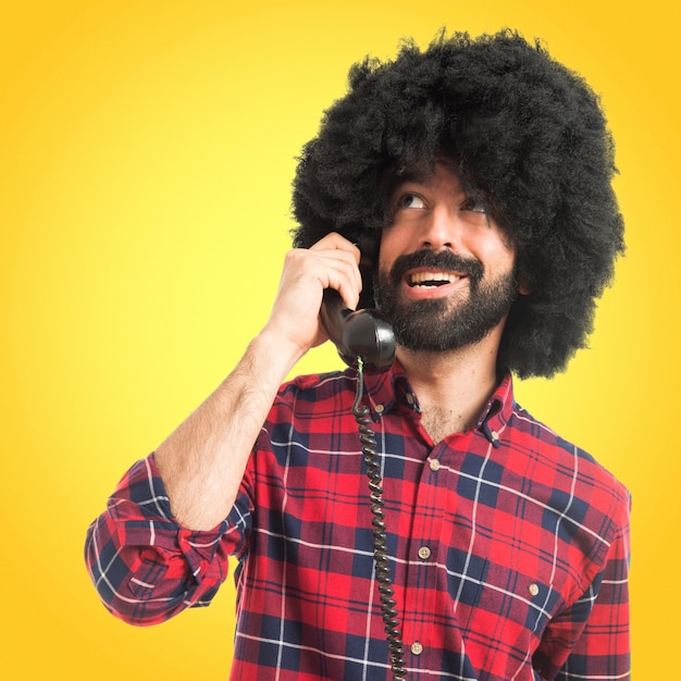 Afro uomo parlando con telefono vintage su sfondo colorato