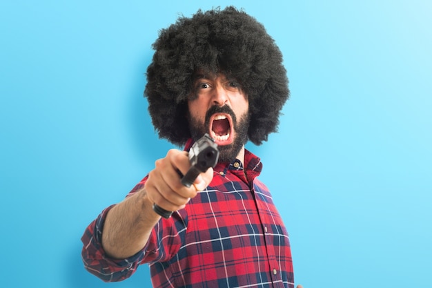 Afro uomo tiro con una pistola su sfondo colorato