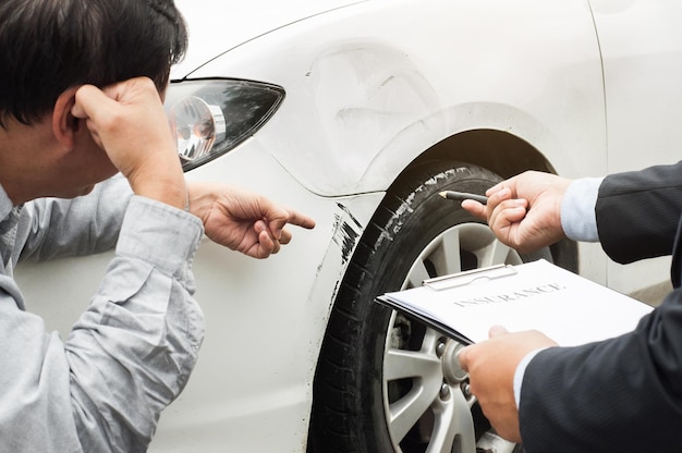 Agente assicurativo che indica un'auto rotta al cliente