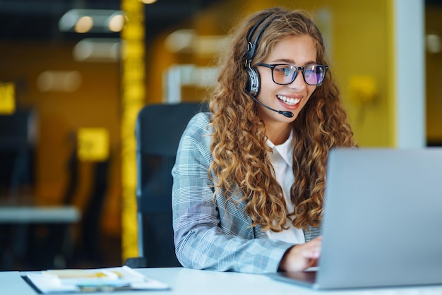 Agente del call center con auricolare che lavora sulla hotline di supporto in un ufficio moderno Videoconferenza