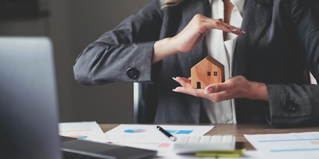 Agente di assicurazione casa femminile con un modello di casa in mano Protezione della casa