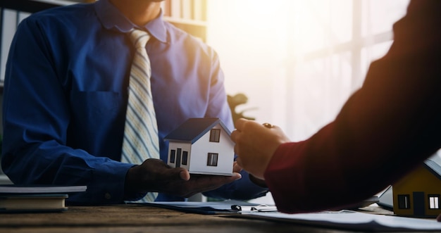 Agente di intermediazione immobiliare che presenta e consulta il cliente per prendere decisioni firmare un contratto di assicurazione per l'acquisto e la vendita di un modello di casa relativo all'offerta di mutuo ipotecario e all'assicurazione sulla casa