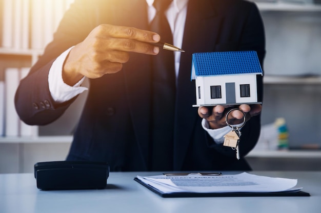 Agente di intermediazione immobiliare che presenta e consulta il cliente per prendere decisioni firmare un contratto di assicurazione per l'acquisto e la vendita di un modello di casa relativo all'offerta di mutuo ipotecario e all'assicurazione sulla casa