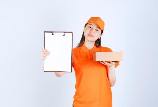 Agente di servizio femminile in uniforme di colore arancione che tiene una scatola di cartone e presenta una lista di controllo per la firma.