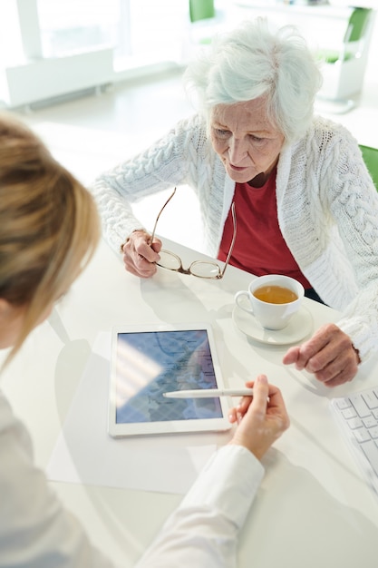 Agente di viaggio che mostra i paesi per le vacanze alla signora senior