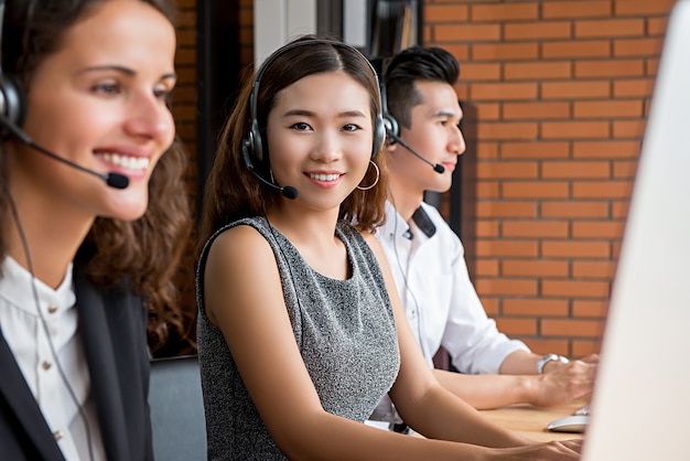 Agente femminile asiatico di servizio di assistenza al cliente di telemarketing che lavora nella call center