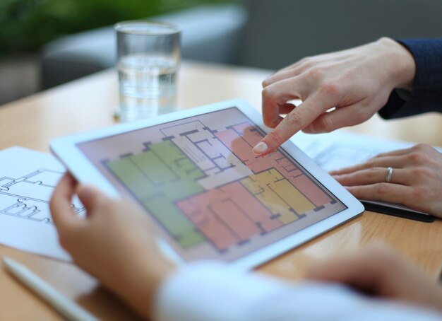 Agente immobiliare che mostra i piani della casa su tablet elettronico
