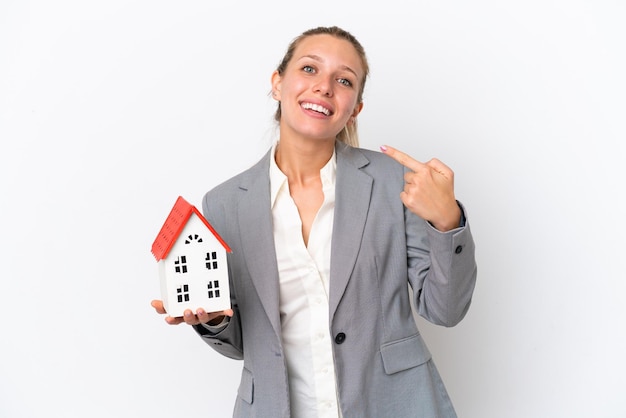 Agente immobiliare donna in possesso di una casa giocattolo isolata su sfondo bianco dando un pollice in alto gesto