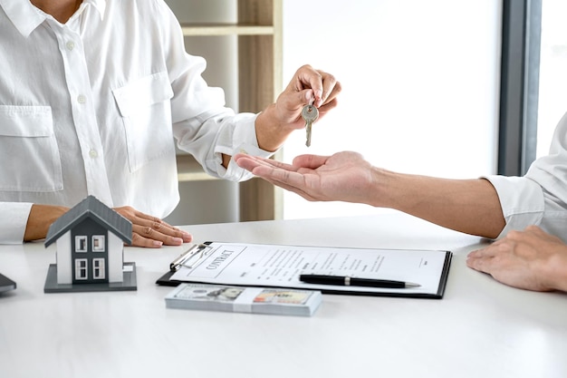 Agente immobiliare Responsabile vendite in possesso di chiavi di archiviazione al cliente dopo aver firmato un contratto di locazione locativa o un contratto di compravendita relativo all'offerta di mutuo ipotecario e all'assicurazione sulla casa