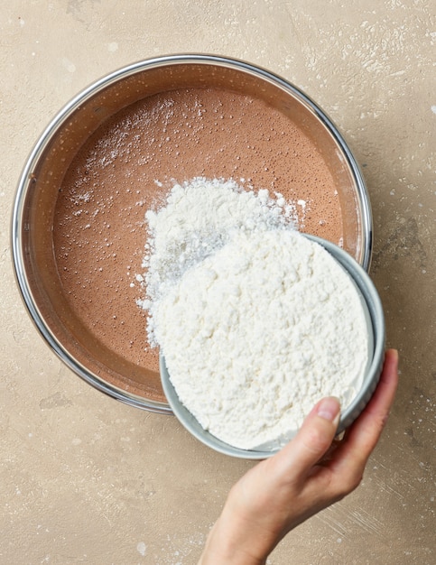 Aggiunta di farina alla ciotola di pasta per torta al cioccolato, vista dall'alto