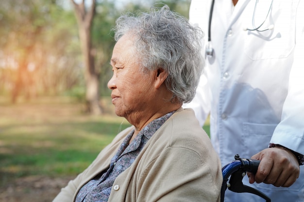 Aggiusti l&#39;aiuto e la cura paziente anziano o anziano asiatico della donna della signora anziana che si siede sulla sedia a rotelle