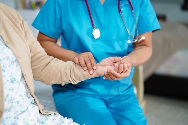 Aggiusti la cattura del polso con il paziente in ospedale infermieristico