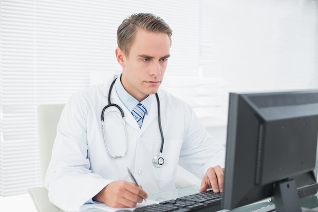 Aggiusti la scrittura della nota mentre per mezzo del computer all&#39;ufficio medico