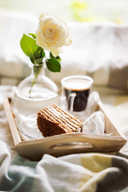 Agglutini con caffè e fiore in vassoio sul letto