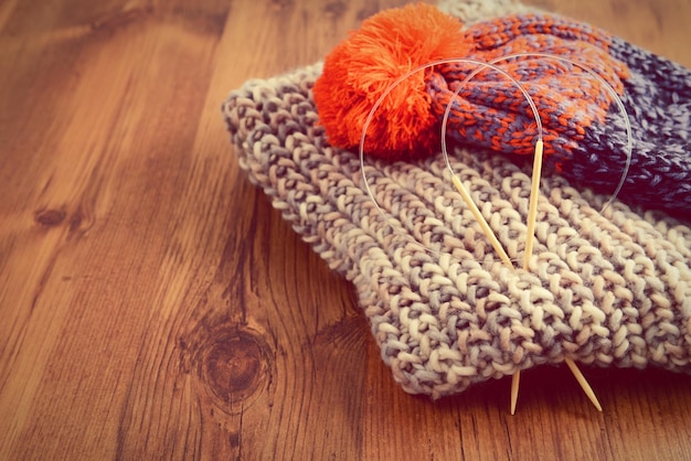 Aghi da maglieria con cappello e sciarpa su un tavolo di legno