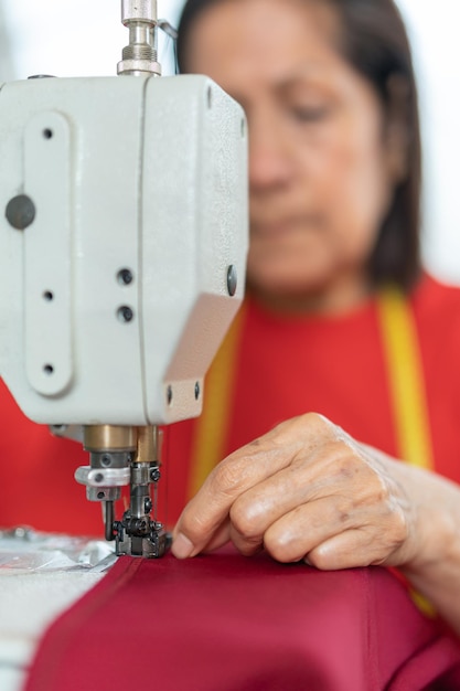 Aghi di una macchina da cucire mentre una donna ci lavora