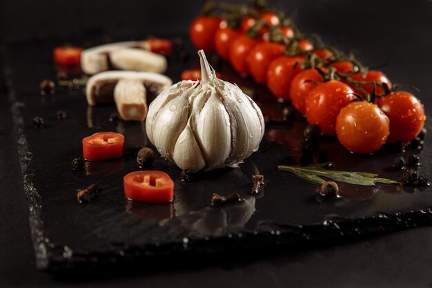 Aglio aglio su fondo nero con pomodori e funghi