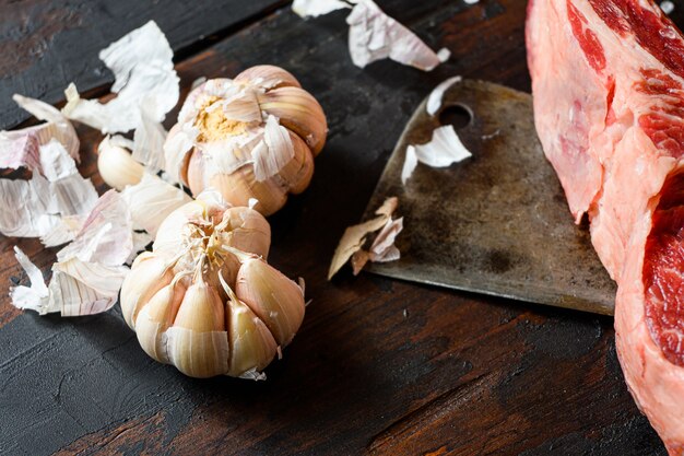 Aglio, che si trova vicino al coltello da taglio con bistecca di manzo di carne cruda.