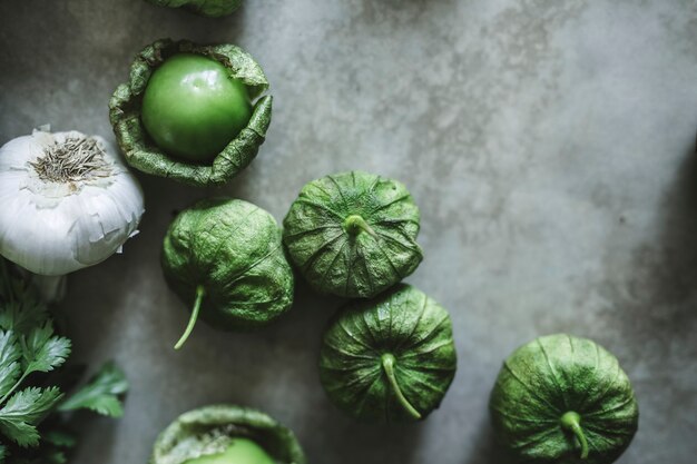 Aglio e tomatillos verdi su un tavolo grigio