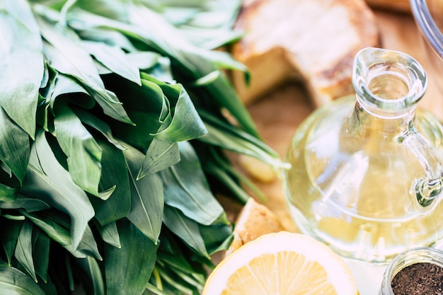 Aglio orsino su un tagliere con bottiglia di olio e limone