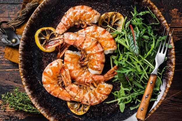 Aglio piccante Gamberi giganti in piastra con insalata Sfondo in legno Vista dall'alto