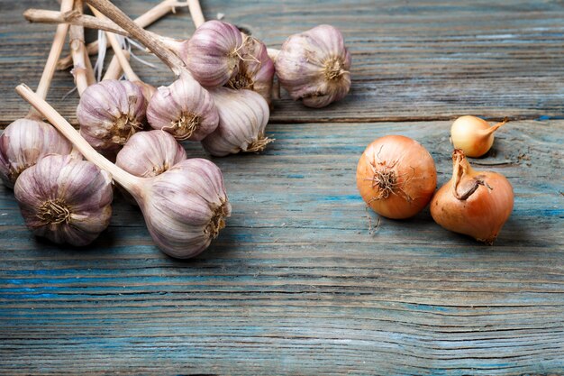 Aglio viola e cipolla arancio su un fondo di legno