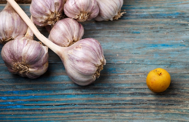 Aglio viola e frutta gialla su un fondo di legno