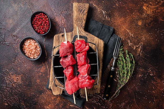 Agnello shish kebab, spiedini di carne cruda con erbe alla griglia. Sfondo scuro. Vista dall'alto.