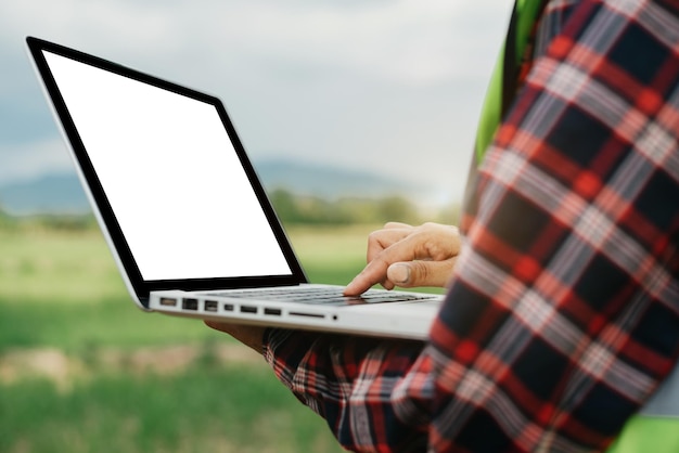 Agricoltore che utilizza il rapporto di controllo del computer portatile dell'agricoltura in fattoria.