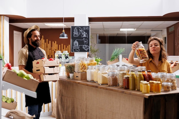 Agricoltore che vive consapevolmente portando casse piene di verdure dal suo orto al supermercato a rifiuti zero. Il fornitore rifornisce il negozio di quartiere locale con prodotti alimentari nutrienti senza conservanti