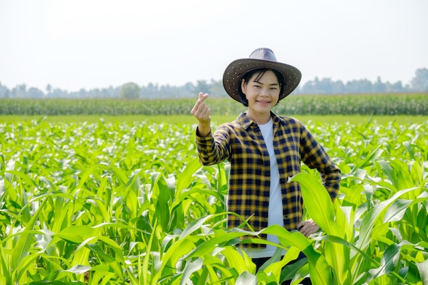 Agricoltore femminile asiatico in camicia a righe che posa al campo di mais