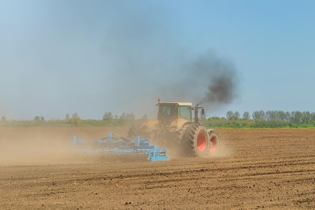 Agricoltore in trattore che prepara coltivatore del letto di semina della terra Paesaggio del trattore agricolo.