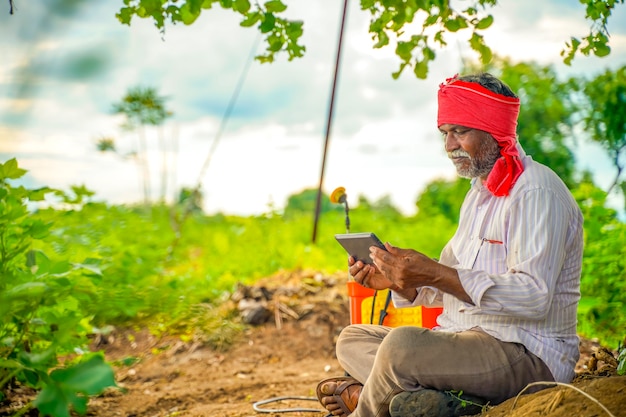 Agricoltore indiano utilizzando il telefono cellulare al campo agricolo
